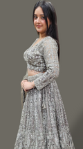 Woman wearing a silver traditional outfit with a plain background